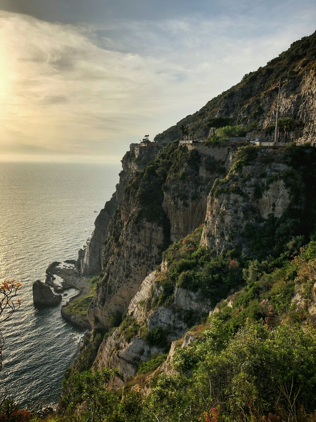Rocky coastal cliffs with small white buildings overlook the sea.